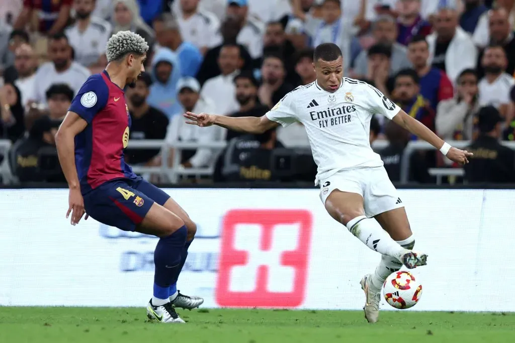 Kylian Mbappé, do Real Madrid, conduz a bola sob pressão de Ronald Araújo, do FC Barcelona, durante a final da Supercopa da Espanha entre Real Madrid e FC Barcelona, no Estádio King Abdullah Sports City, em 12 de janeiro de 2025, em Jidá, Arábia Saudita.