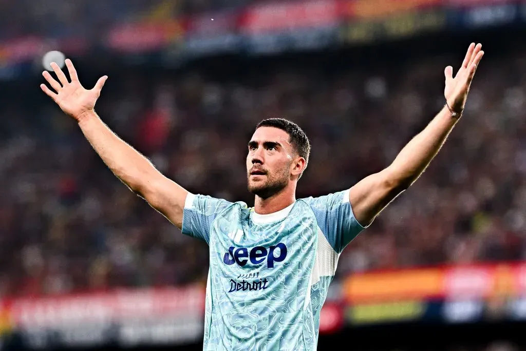Dusan Vlahovic vestindo uma camisa azul da Juventus e comemorando com os braços erguidos. Foto: Simone Arveda/Getty Images