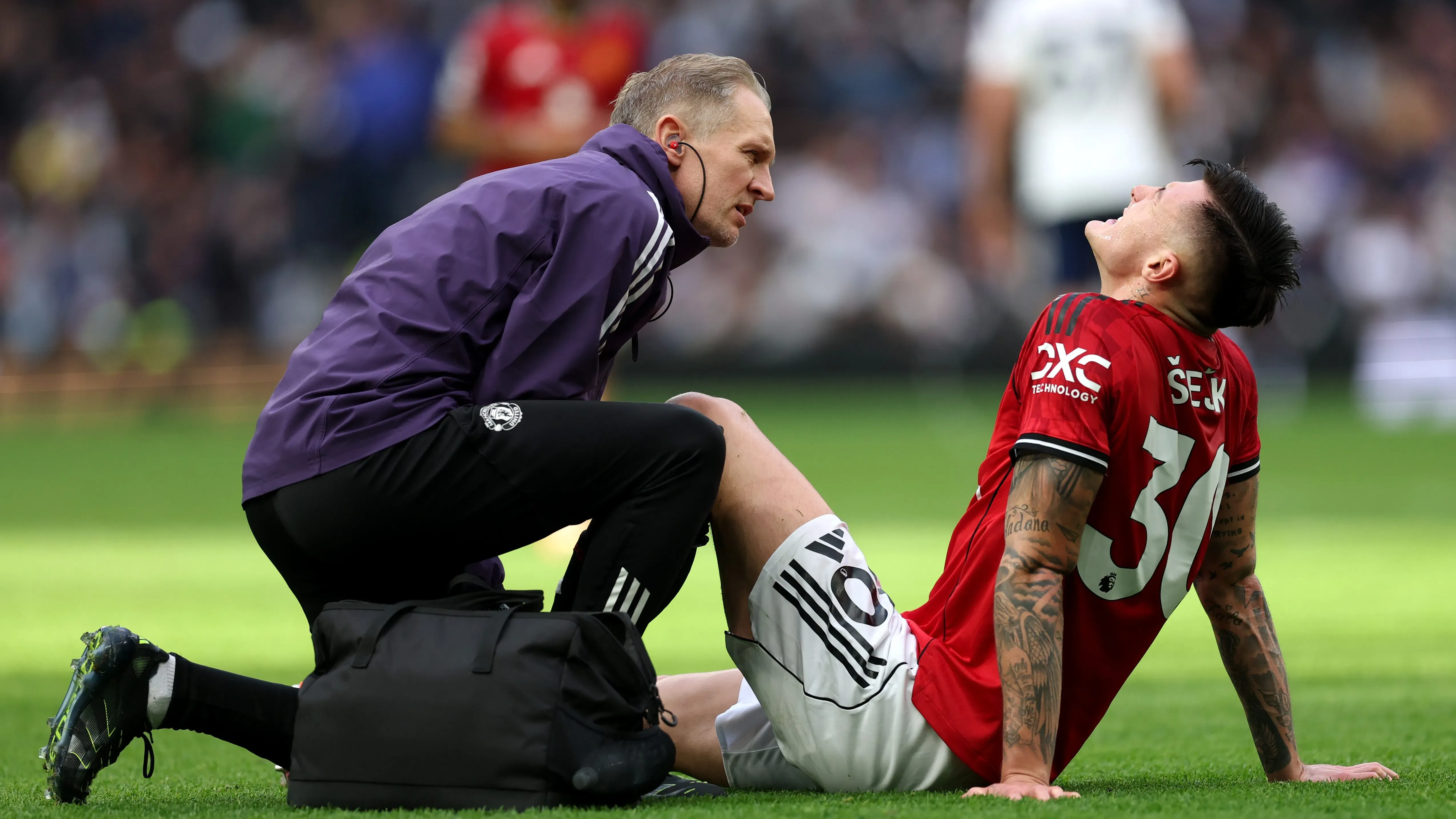 Benjamin Sesko com camisa vermelha, recebendo atendimento do médico do Manchester United. Foto: Julian Finney/Getty Images