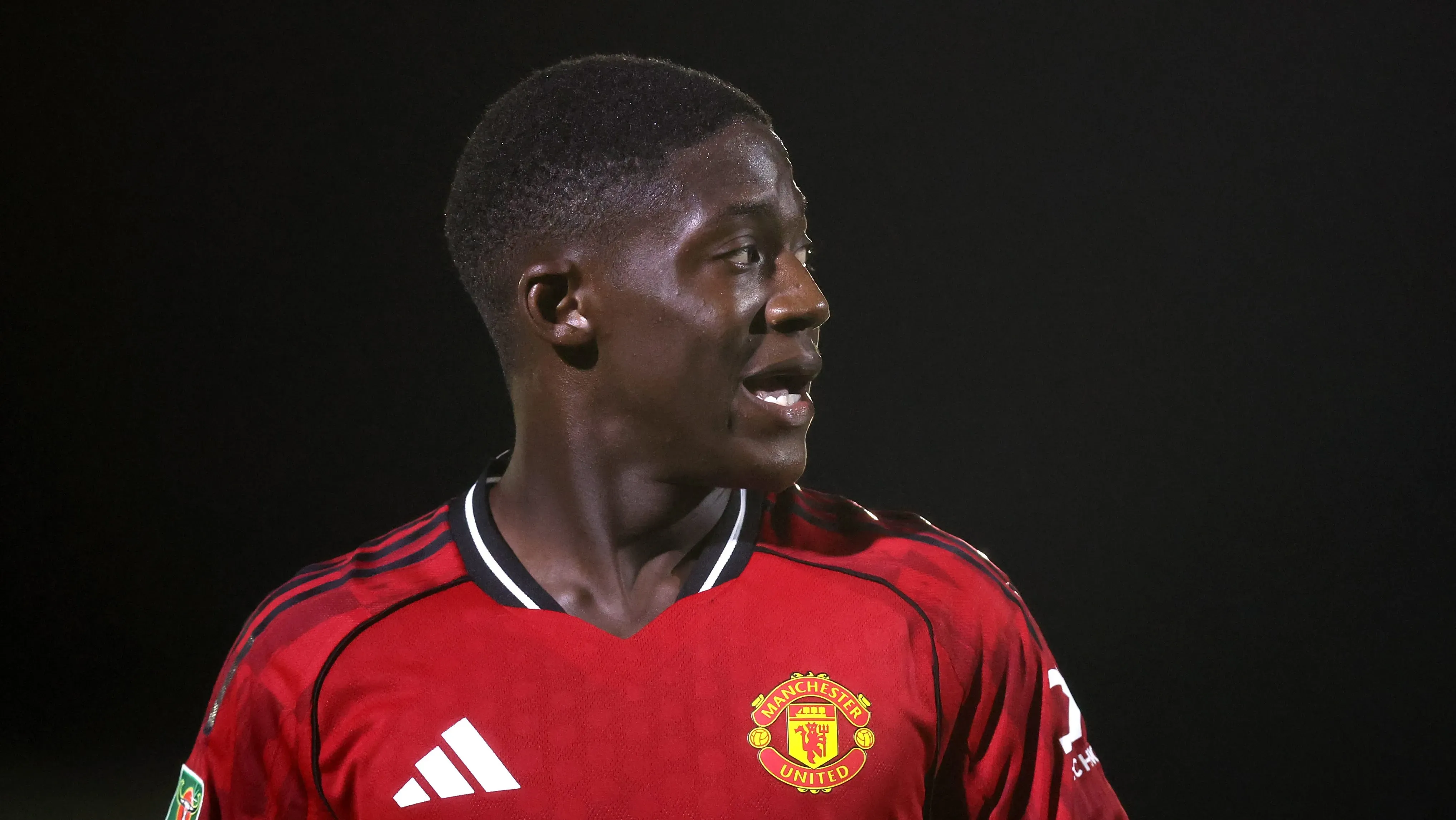 Mainoo usa a camisa do United e olha para o seu lado esquerdo